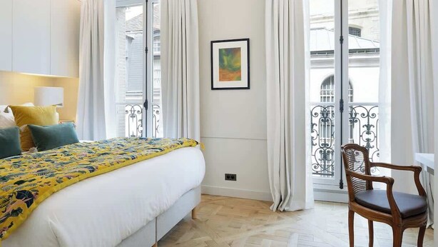 A hotel room with a bed, a chair, a window with curtains, and a framed picture on the wall. - A Splendide 3-BR/3BA close to Le Bon Marché (Paris)