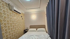 A neatly made bed with white linens and towels, a headboard, and a wall-mounted air conditioner. - Thon Thean Hotel  (Phnom Penh)