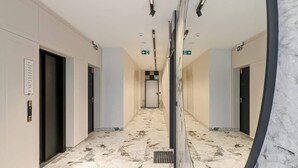 A hallway with marble flooring, doors, and emergency exit signs. - Modern Apartment | Parking, Balcony and Workspace (Gdansk)