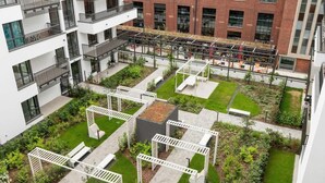 A multi-story building with balconies, a rooftop garden, and a courtyard with seating areas. - Modern Apartment | Parking, Balcony and Workspace (Gdansk)