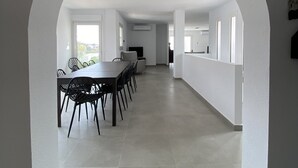 Ein modernes Interieur mit Essbereich, weißen Wänden und einem großen Bogen, der in einen weiteren Raum führt.