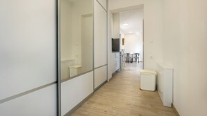 A hallway with a wooden floor, a trash bin, and a white wall with a door. - Deluxe apartment Noeli (Krvavica)
