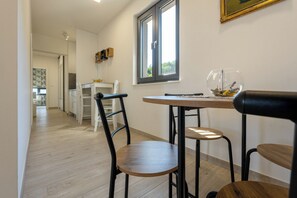 A modern kitchen with white cabinets, a wooden countertop, and a window with a view of greenery. - Deluxe apartment Noeli (Krvavica)