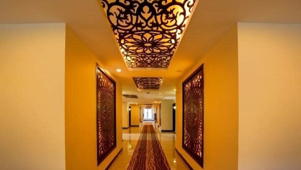 A hallway with a patterned ceiling and walls, leading to a bright room. - Avari Xpress Skardu (Skardu)