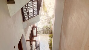 A staircase with a metal railing, potted plants, and a view of a garden outside.