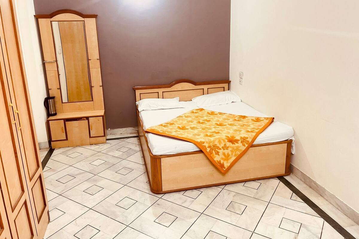 A bedroom with a bed, a wooden wardrobe, and a mirror.