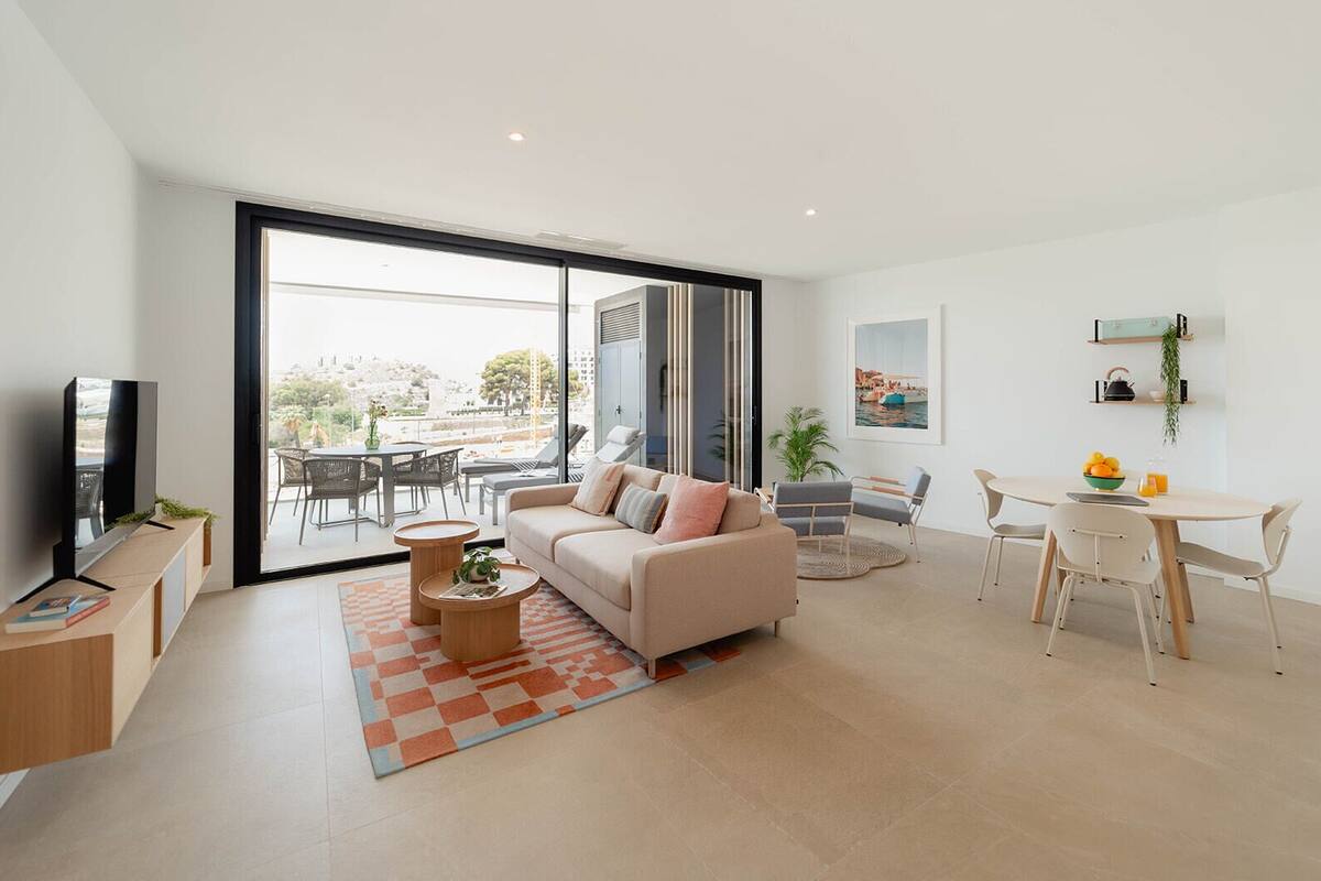 A modern living room with a sofa, coffee table, and dining area.