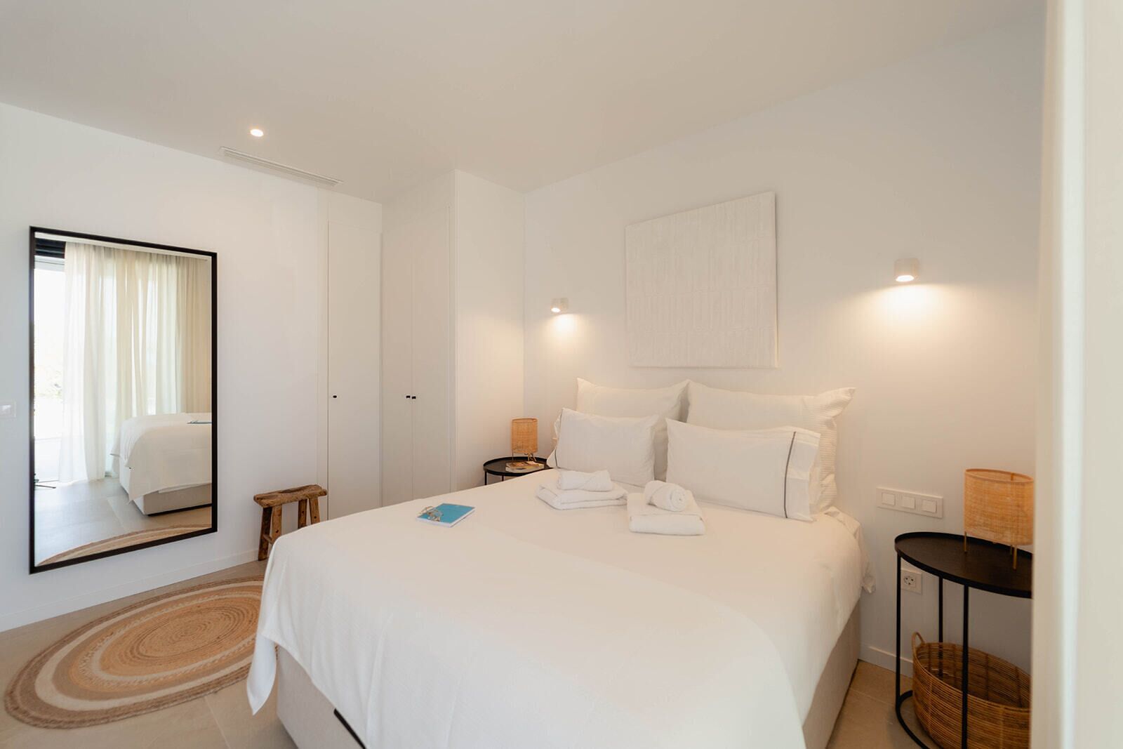 Une chambre à coucher avec un grand lit, une table de chevet, un miroir et une commode.