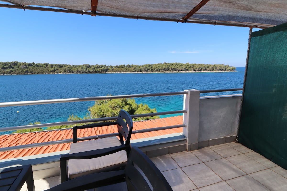 A balcony with a view of a lake and forest.