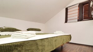 Un letto singolo con una coperta verde, due cuscini e asciugamani bianchi piegati.