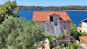 Un edificio dal tetto in tegole rosse che si affaccia su un corso d'acqua, immerso nel verde.