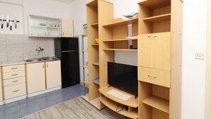 Una cucina moderna con mobili in legno, un frigorifero nero, una TV integrata e un piccolo ripiano con utensili da cucina.