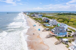 A coastal property with beach access, a pier, and a large house with multiple decks.