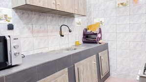 Een moderne keuken met grijze en beige tegels, een ingebouwde magnetron en houten kastjes.