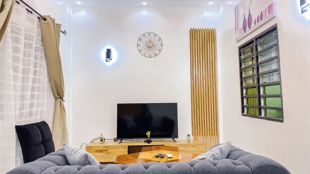 Een moderne woonkamer met een flatscreen televisie, een houten salontafel en een grijze bank.