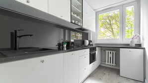 Una cocina moderna con armarios blancos, una encimera negra y un horno empotrado.