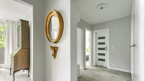 Un pasillo con un armario de madera, un espejo con marco dorado y una puerta con paneles negros.