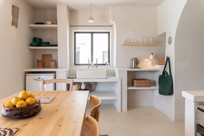 Une cuisine avec une table en bois, des chaises, une fenêtre et divers ustensiles de cuisine.