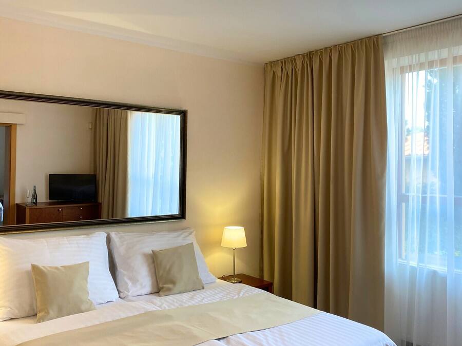 Een hotelkamer met een groot bed, een bedlamp, een flatscreen-tv en een raam met gordijnen.