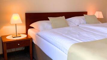 Une chambre d’hôtel avec un lit, deux lampes de chevet et une table de nuit en bois.