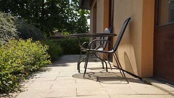 A patio with a table and chairs, a tiled walkway, and a building with a beige wall.