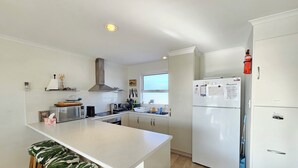 A modern kitchen with white cabinets, a central island with bar stools, a built-in oven, and a refrigerator. - 300 Steps - 300 Steps to Robes' famous Longbeach - Pet friendly Inside (Robe)