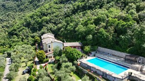 A villa with a swimming pool surrounded by lush greenery and a mountainous backdrop.