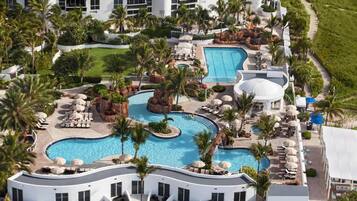 Un resort con varias piscinas, palmeras y zonas de descanso.
