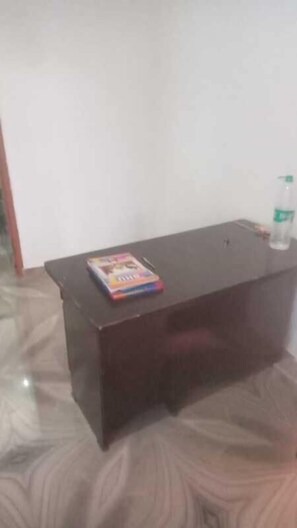 A dark wooden desk with a colorful book and a bottle of water. - Priyanshu Residency & Kartik Inn Guest  (Varanasi)