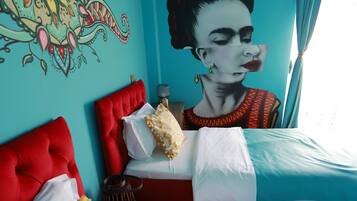 A room with two beds, a mural on the wall, and a window with curtains.