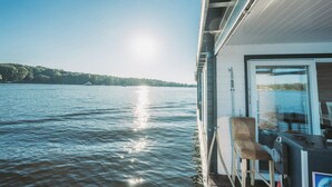 Ein Boot mit Liegestuhl und Tisch, das auf einen ruhigen See mit blauem Himmel blickt.