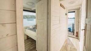 Ein schmaler Holzkorridor, der zu einem Bett mit Seeblick und Booten führt.