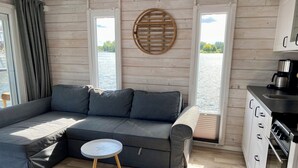 Eine moderne Hütte mit einem grauen Ecksofa, einem kleinen runden Tisch und einer Küchenzeile.