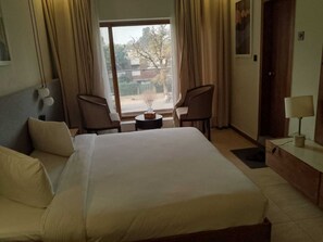 A hotel room with a large bed, two chairs, a small table, and a view of the outside. - Hotel Star (Islamabad)