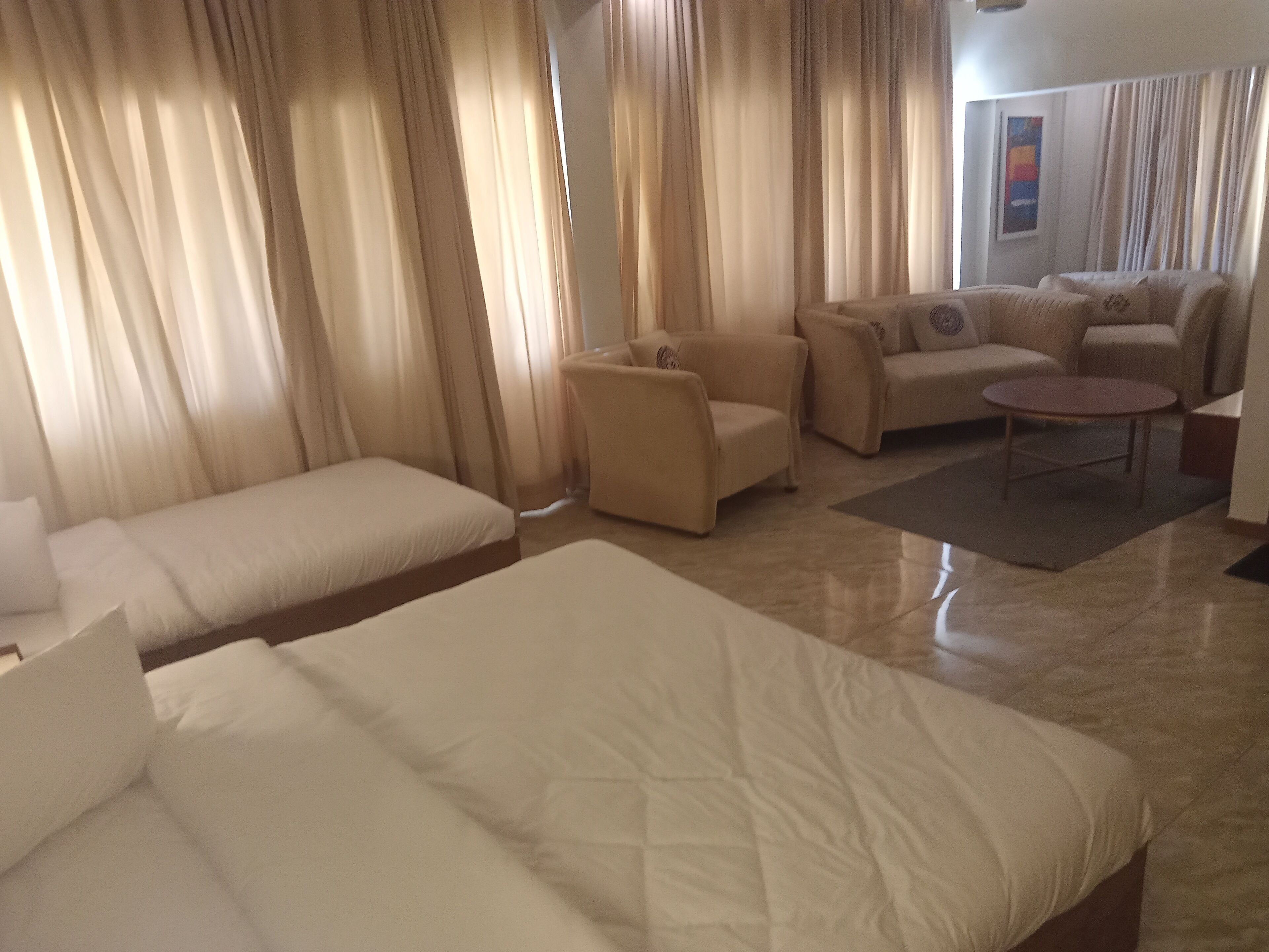 Ein Hotelzimmer mit zwei Betten, einem Schlafsofa, einem Sessel und einem kleinen Tisch.