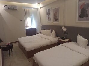 A hotel room with two beds, a desk, a chair, and a window with curtains. - Hotel Star (Islamabad)