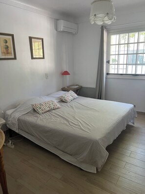 Une chambre avec un lit, une fenêtre, un climatiseur et une lampe.
