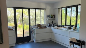 Una cucina moderna con ampie finestre, forno integrato e un carrello in metallo nero.