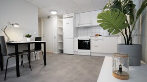 A modern kitchen with white cabinets, a built-in oven, and a dining area with a table and chairs. - Forenom Project Accommodation Eslöv (Eslöv)