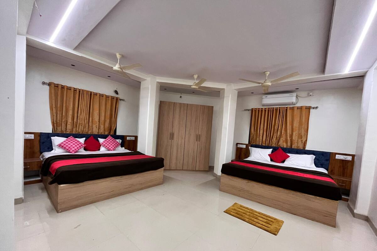 Een hotelkamer met twee bedden, een kledingkast, een plafondventilator en een airconditioning.