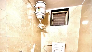 Een kleine badkamer met tegels, een toilet, een douche en een handdroger.