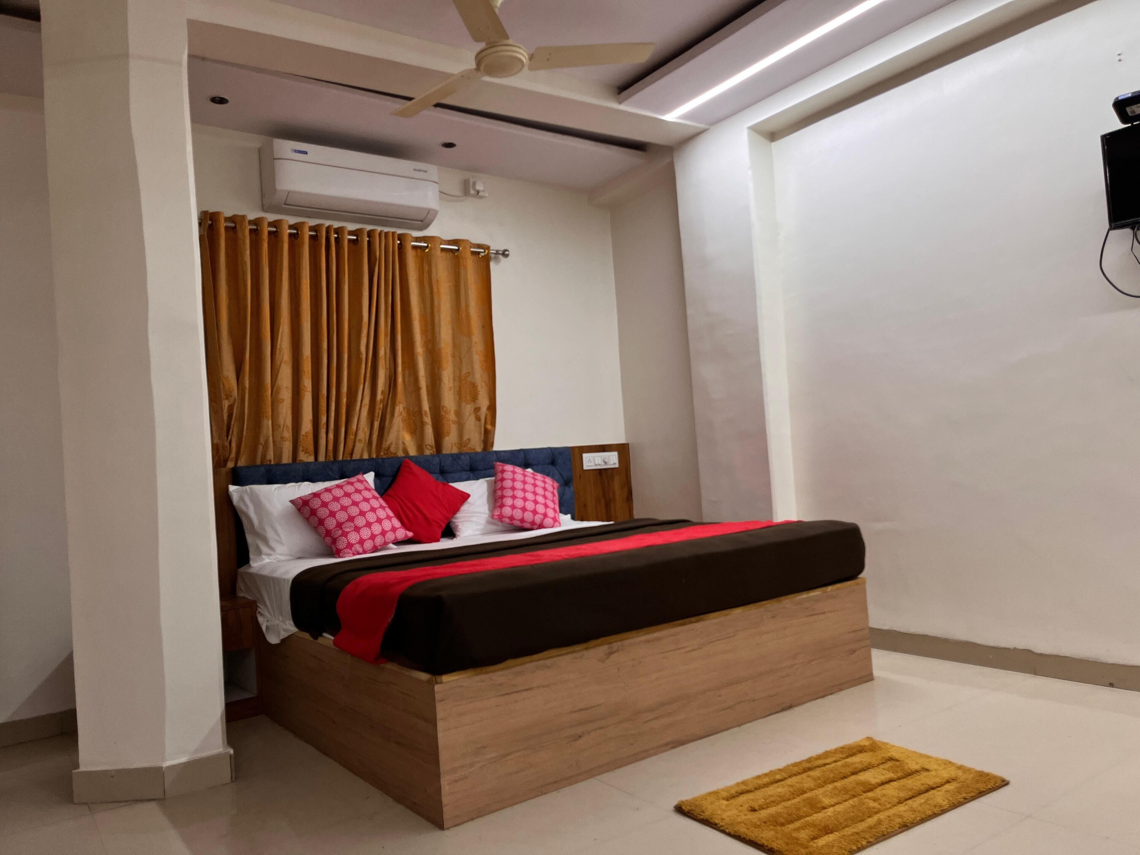 Un dormitorio moderno con una cama de madera, un ventilador de techo y un equipo de aire acondicionado pequeño.