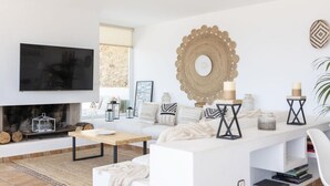 Un soggiorno moderno con camino, arredi bianchi e oggetti decorativi.