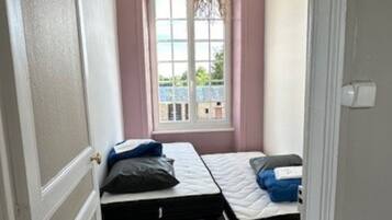 Una habitación pequeña con dos camas individuales, una ventana con vistas y una lámpara colgante.