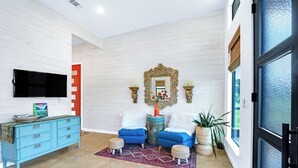 Ein modernes Wohnzimmer mit einem blauen Sofa, einem Holz-Fernsehschrank und einem dekorativen Spiegel.