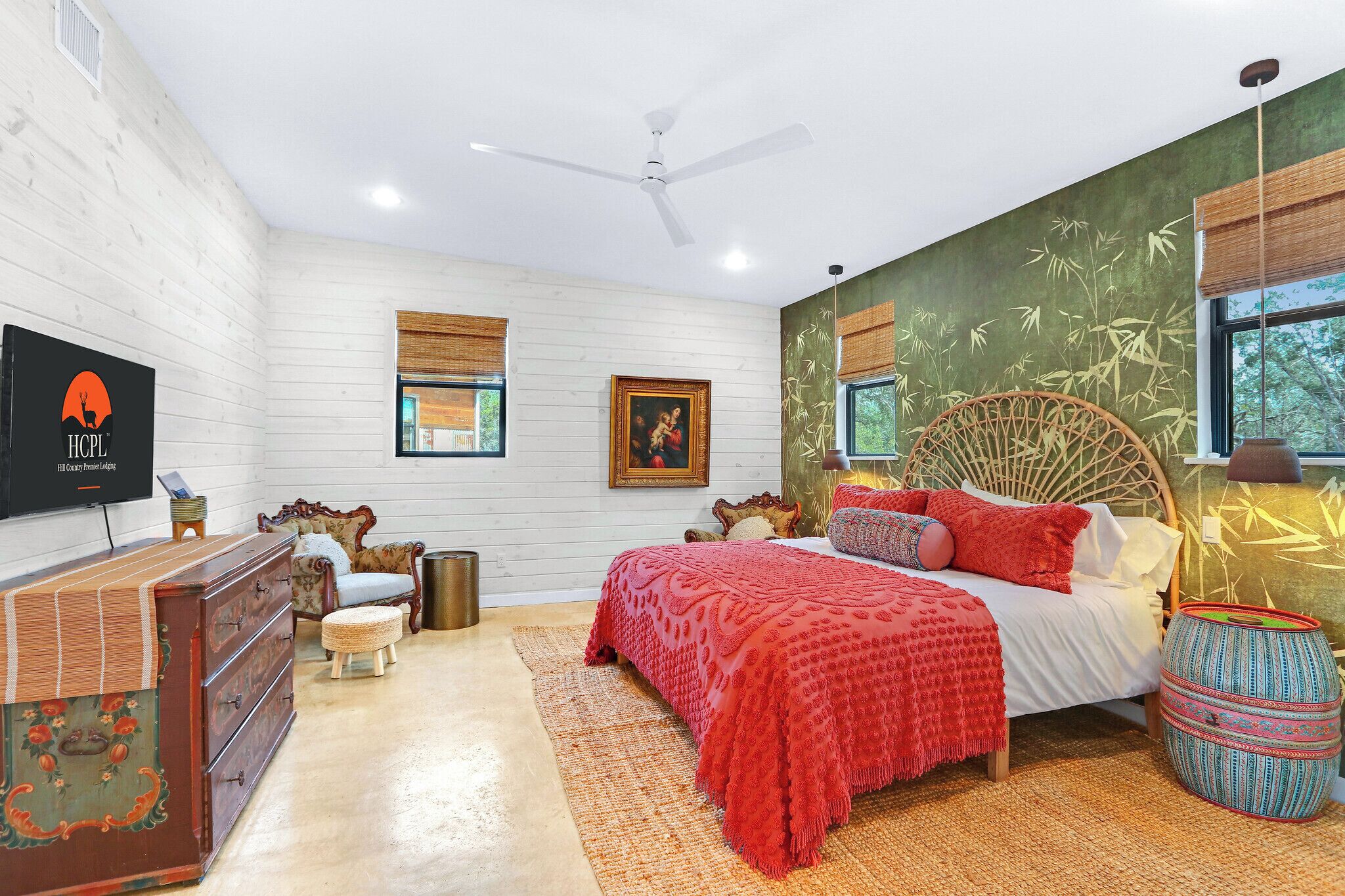 Une chambre à coucher comprenant un lit, une commode, un téléviseur et un mur décoré d’une fresque représentant des bambous.