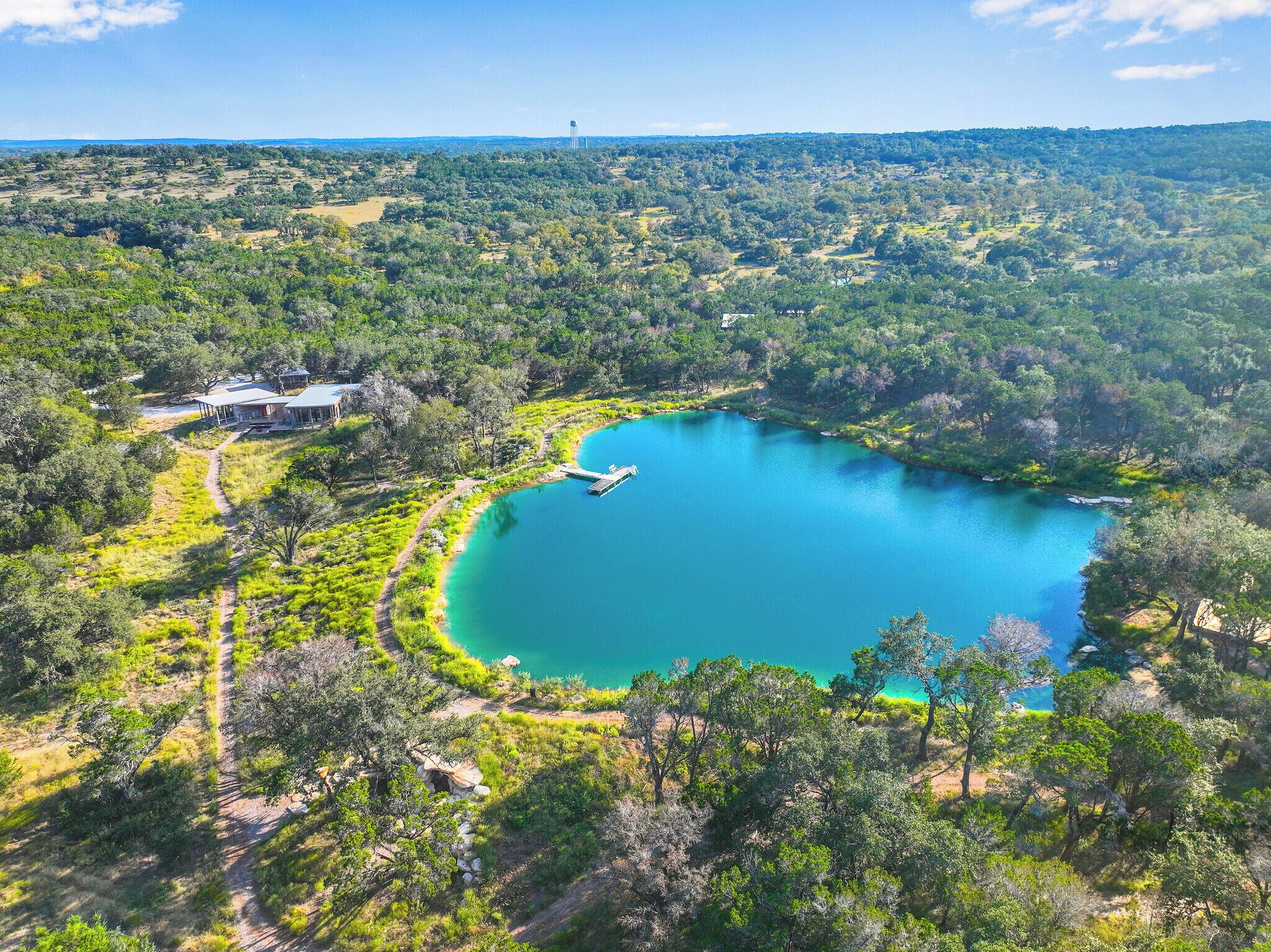 Un lac entouré d’une forêt dense, une jetée et un bâtiment doté d’une zone abritée.