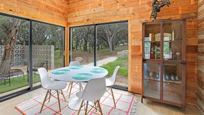 Un intérieur en bois avec une table ronde, des chaises blanches et un meuble vitré avec des étagères.