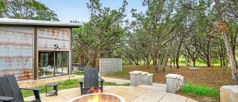 An outdoor patio with a fire pit, seating, and a modern building with large windows.