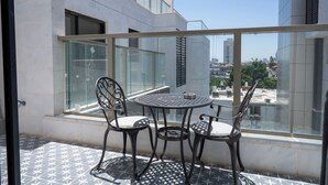 A balcony with a glass railing, two chairs, and a small round table. - O&O - 2 BR Stylish & Modern Apartment (Bat Yam)